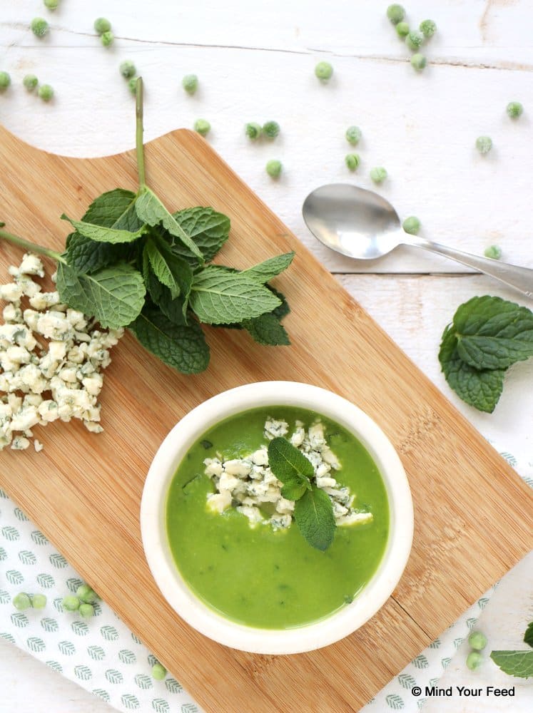 Koude doperwtensoep met munt geserveerd in een glaasje, frisse groene soep met erwt, munt en romige kaas als feestelijk voorgerecht.
