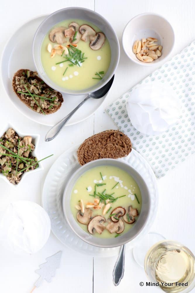 Pastinaak appelsoep met geroosterde amandelen als feestelijk voorgerecht voor Kerst, romige pastinaaksoep met appel en knapperige amandelen in een kom.