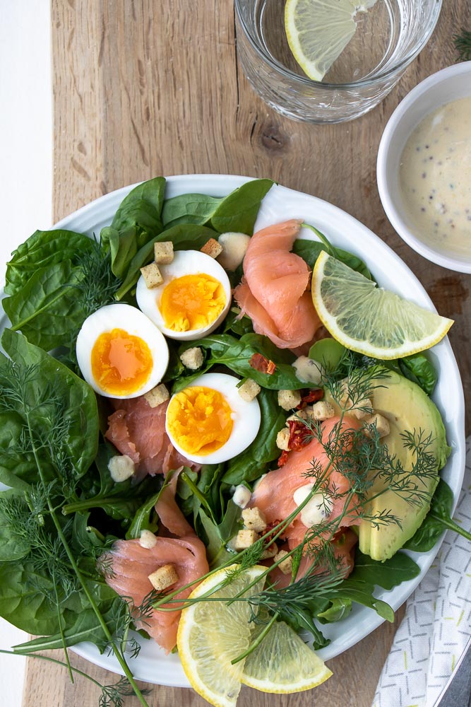 Salade met gerookte zalm, spinazie, avocado en gekookt ei. Makkelijk recept voor lunch salade met zelfgemaakte honing mosterd dressing