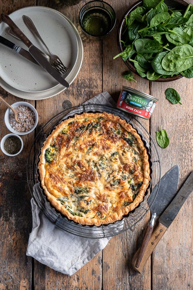 Verschillende ingrediënten voor de zalm quiche, waaronder wilde zalm, knapperige broccoli en frisse doperwten. Hartige taart met zalm en spinazie