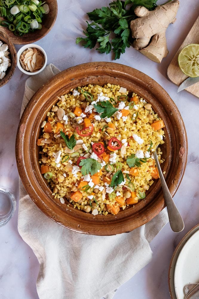 Recept voor Marokkaanse bloemkoolcouscous met kikkererwten, feta en geroosterde amandelen, op smaak gebracht met kurkuma, kaneel en gerookt paprikapoeder.