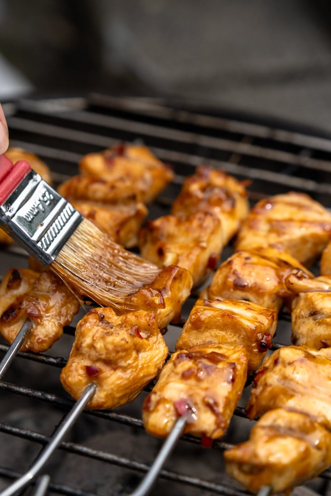 Zelf kipsaté maken. Recept voor geroosterde kipsaté van de BBQ, afgelakt met marinade en geserveerd met satésaus en komkommersalade.