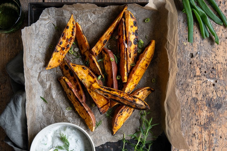 Geroosterde zoete aardappel wedges van de BBQ, geserveerd met een frisse yoghurt-dip van dille, citroen en knoflook