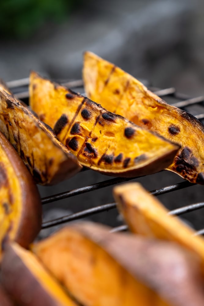 Geroosterde zoete aardappel wedges van de BBQ, geserveerd met een frisse yoghurt-dip van dille, citroen en knoflook