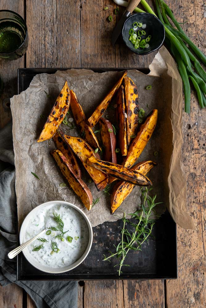 Geroosterde zoete aardappel wedges van de BBQ, geserveerd met een frisse yoghurt-dip van dille, citroen en knoflook