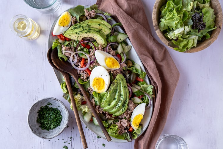 Salade met tonijn, avocado en ei op een bord met verse groenten, paprika, rode ui en groene olijven – makkelijke lunchsalade met tonijn uit blik.