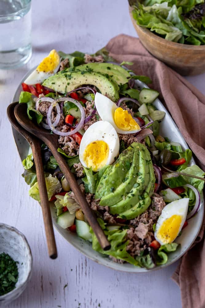 Salade met tonijn, avocado en ei op een bord met verse groenten, paprika, rode ui en groene olijven – makkelijke lunchsalade met tonijn uit blik.
