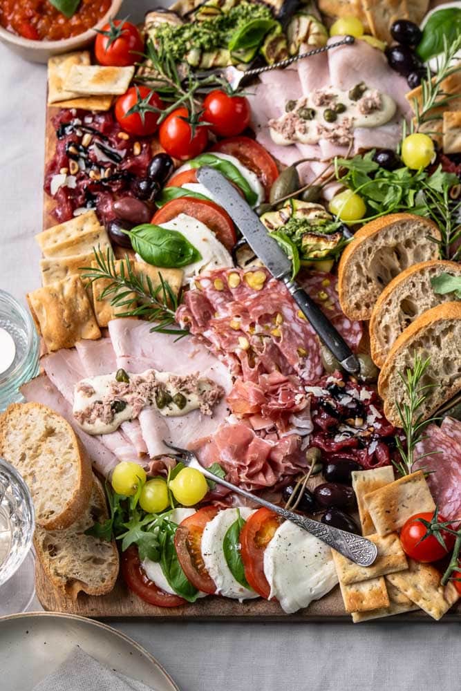 Italiaanse antipasti plank met klassieke Italiaanse hapjes zoals vleeswaren, kazen, bruschetta en gegrilde groenten, feestelijk geserveerd om te delen.