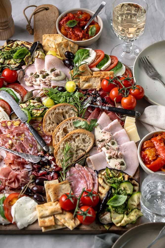 Italiaanse antipasti plank met klassieke Italiaanse hapjes zoals vleeswaren, kazen, bruschetta en gegrilde groenten, feestelijk geserveerd om te delen.