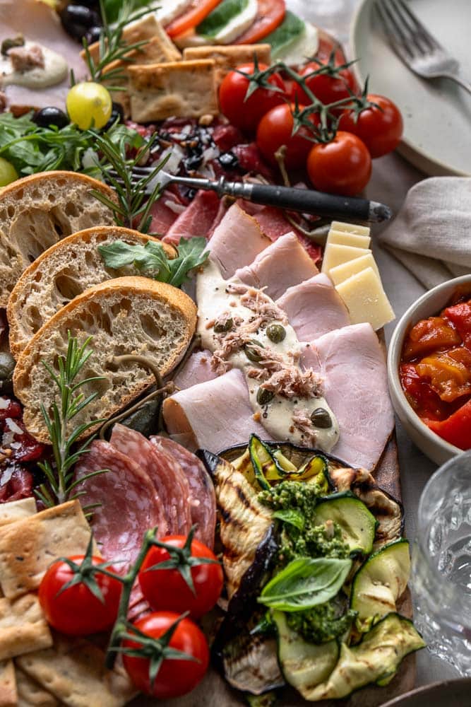 Italiaanse antipasti plank met klassieke Italiaanse hapjes zoals vleeswaren, kazen, bruschetta en gegrilde groenten, feestelijk geserveerd om te delen.