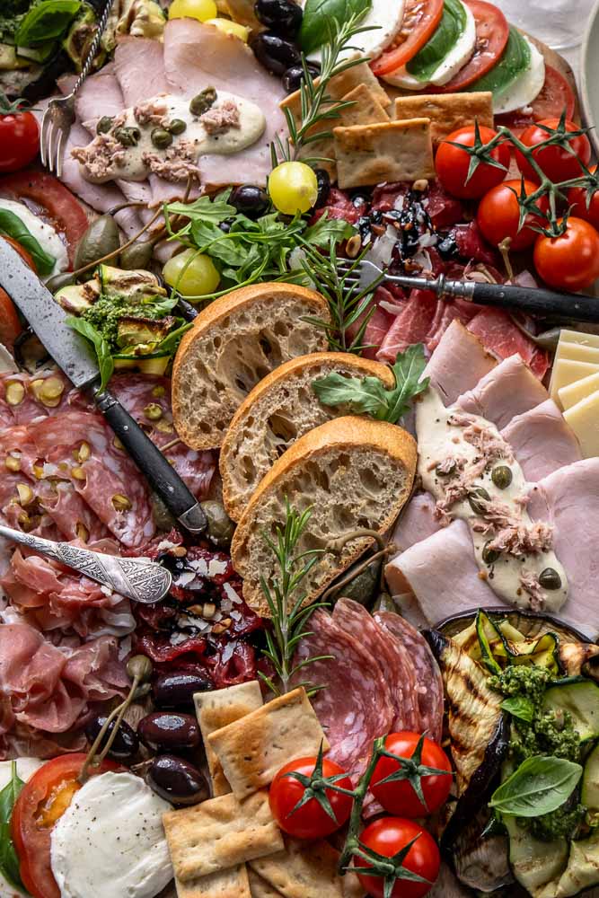 Italiaanse antipasti plank met klassieke Italiaanse hapjes zoals vleeswaren, kazen, bruschetta en gegrilde groenten, feestelijk geserveerd om te delen.