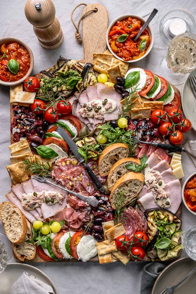 Italiaanse antipasti plank met klassieke Italiaanse hapjes zoals vleeswaren, kazen, bruschetta en gegrilde groenten, feestelijk geserveerd om te delen.