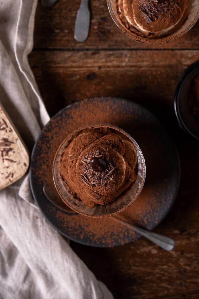 Tiramisu in een glaasje met mascarpone, slagroom, lange vingers en cacao; feestelijk Italiaans dessert geserveerd in laagjes.