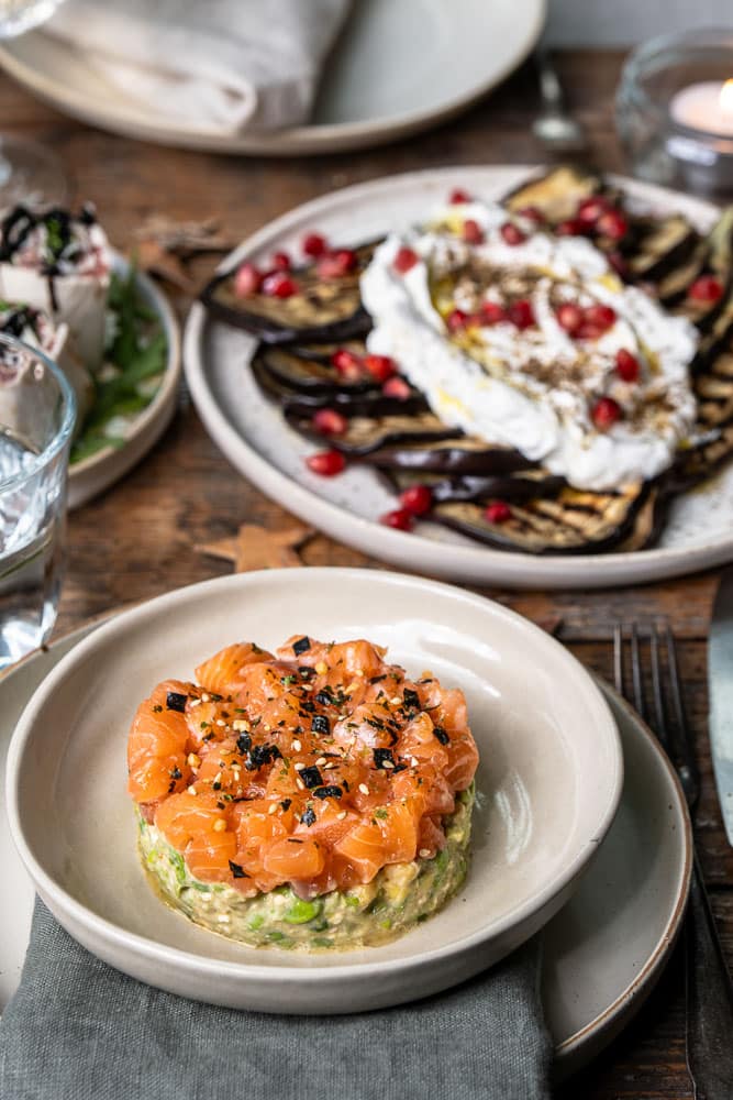 Torentje van zalmtartaar met avocado, edamame boontjes en mango, opgemaakt met een kookring als feestelijk voorgerecht.