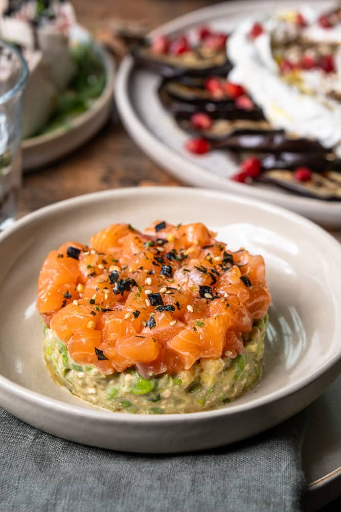 Torentje van zalmtartaar met avocado, edamame boontjes en mango, opgemaakt met een kookring als feestelijk voorgerecht.