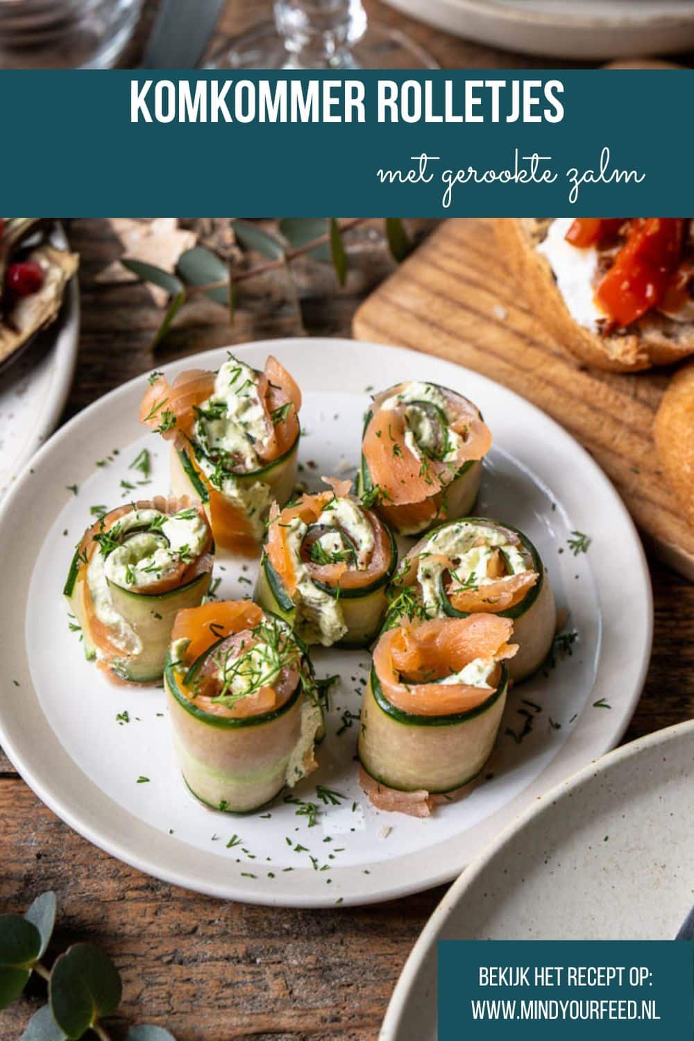 Komkommerrolletjes met zalm en roomkaas, opgerold tot frisse hapjes en gegarneerd met dille.