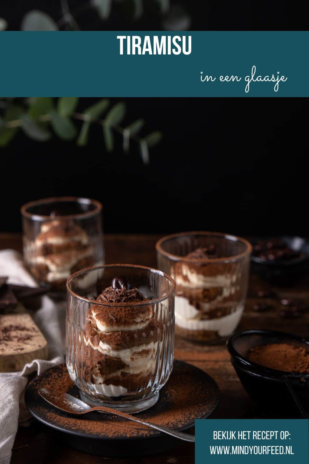 Tiramisu in een glaasje met mascarpone, slagroom, lange vingers en cacao; feestelijk Italiaans dessert geserveerd in laagjes.