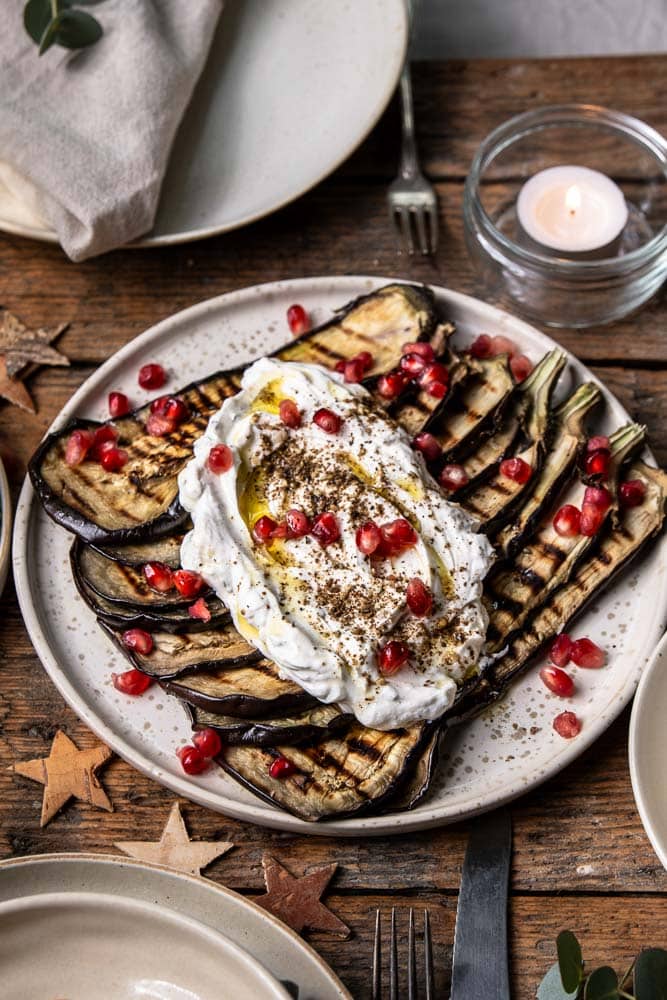 Gegrilde aubergine carpaccio met yoghurt, za’atar en granaatappel als vegetarisch voorgerecht.