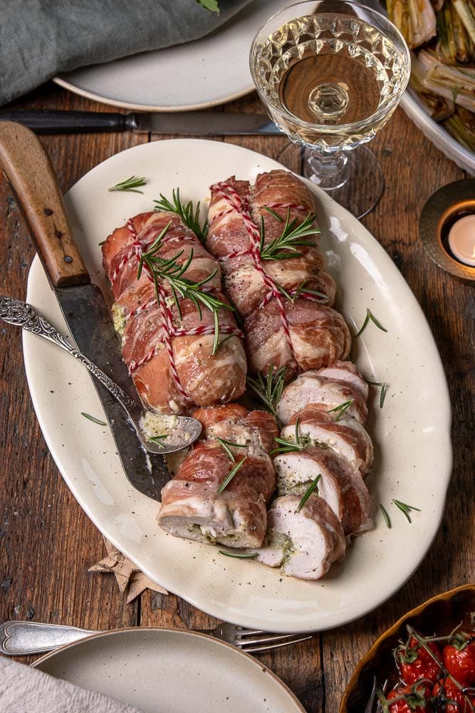 Kip rollade gevuld met mascarpone en pesto, omwikkeld met prosciutto en goudbruin gebakken in de oven.