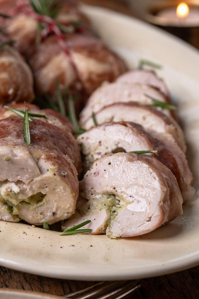 Feestelijke kip rollade met een vulling van pesto en mascarpone en een kruidige prosciutto buitenlaag.
