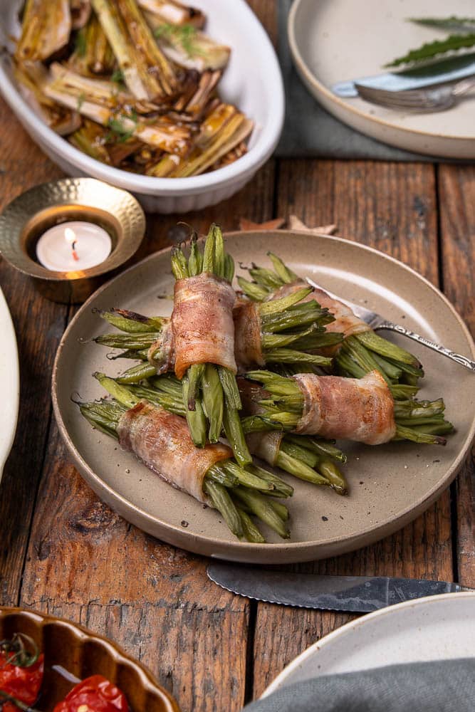 Sperzieboontjes met spek uit de oven; pakketjes van voorgekookte groene bonen omwikkeld met ontbijtspek, goudbruin en krokant gebakken, feestelijk bijgerecht voor Kerst.