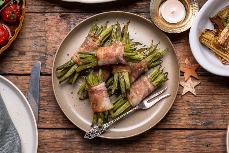 Sperzieboontjes met spek uit de oven; pakketjes van voorgekookte groene bonen omwikkeld met ontbijtspek, goudbruin en krokant gebakken, feestelijk bijgerecht voor Kerst.