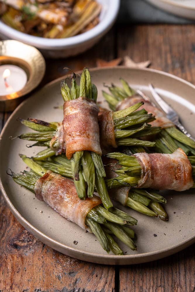 Sperzieboontjes met spek uit de oven; pakketjes van voorgekookte groene bonen omwikkeld met ontbijtspek, goudbruin en krokant gebakken, feestelijk bijgerecht voor Kerst.