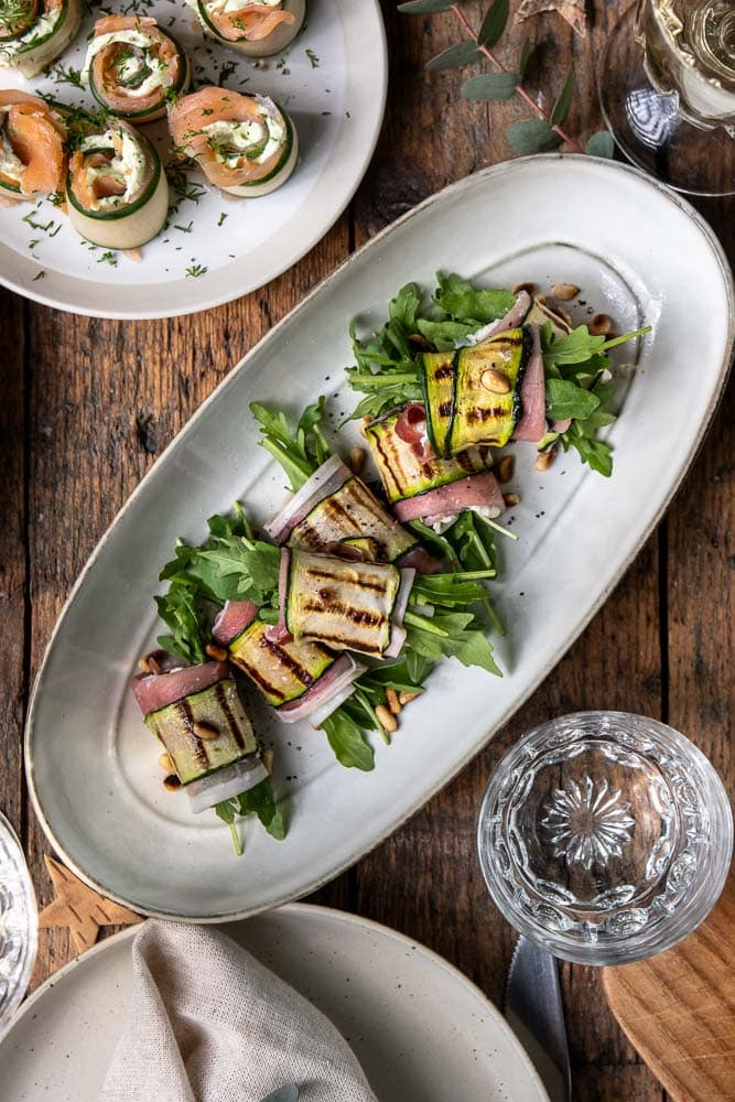 Feestelijk recept voor courgette rolletjes met ricotta, prosciutto, pijnboompitten en rucola; een licht en luxe borrelhapje of voorgerecht dat makkelijk vooraf te maken is.