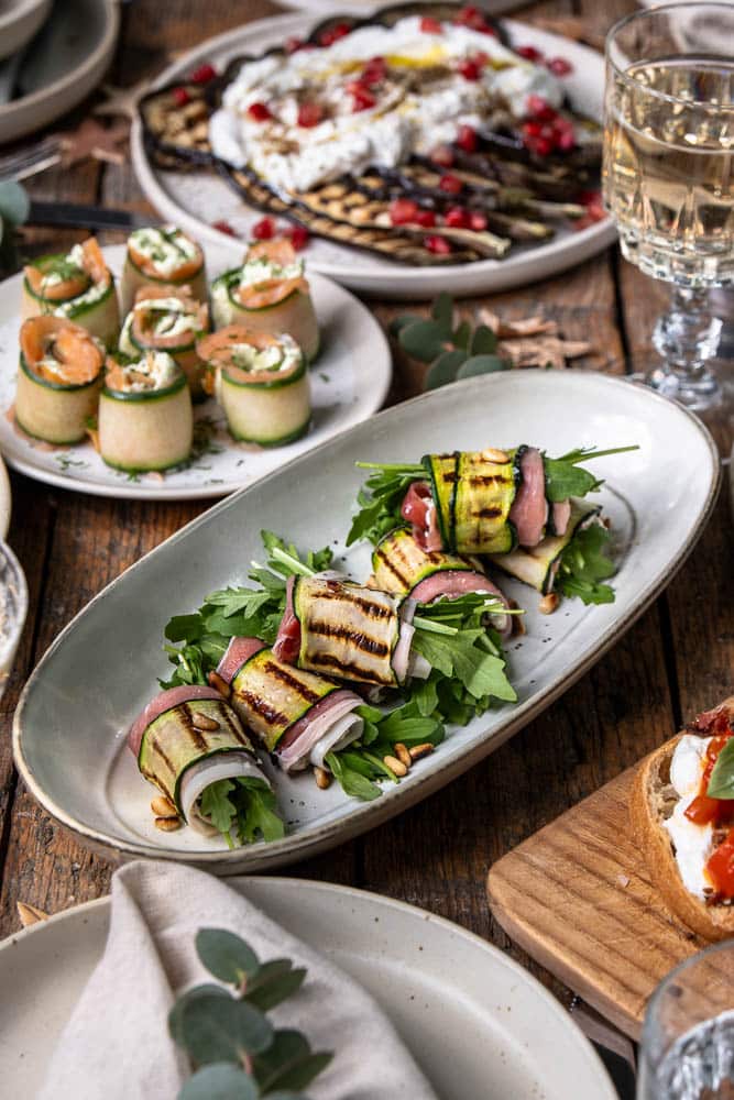 Feestelijk recept voor courgette rolletjes met ricotta, prosciutto, pijnboompitten en rucola; een licht en luxe borrelhapje of voorgerecht dat makkelijk vooraf te maken is.