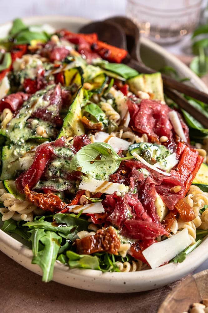 Carpaccio salade met volkoren pasta, gegrilde groenten, rucola, Parmezaanse kaas en pijnboompitten. Deze carpaccio salade kun je maken als maaltijdsalade of luxe lunch. Ook goed voor bijvoorbeeld een picknick!