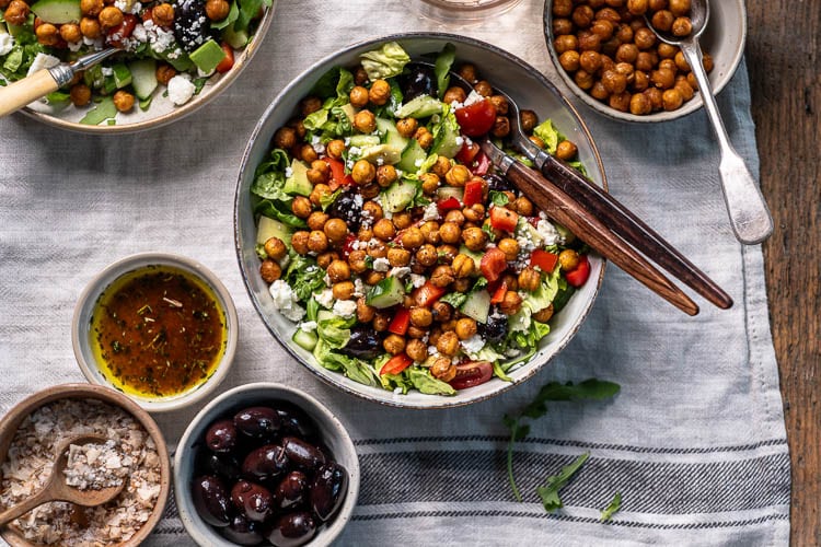 Kikkererwten salade met feta, geroosterde kikkererwten, rucola en balsamico dressing in een kom.