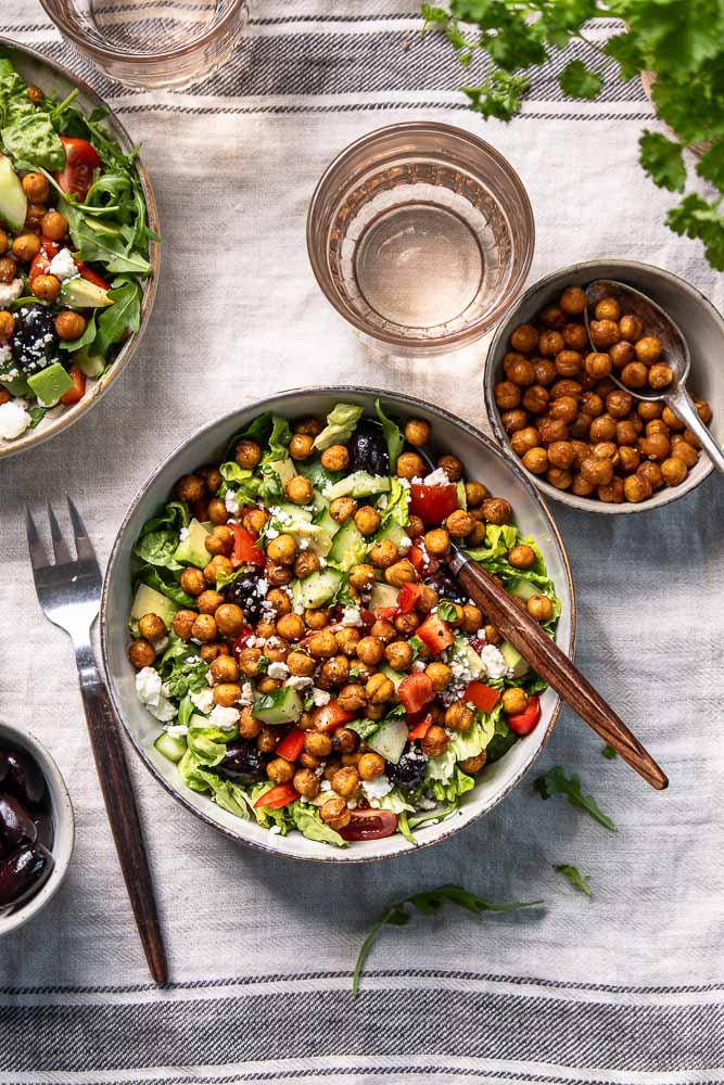 Kikkererwten salade met feta, geroosterde kikkererwten, rucola en balsamico dressing in een kom.