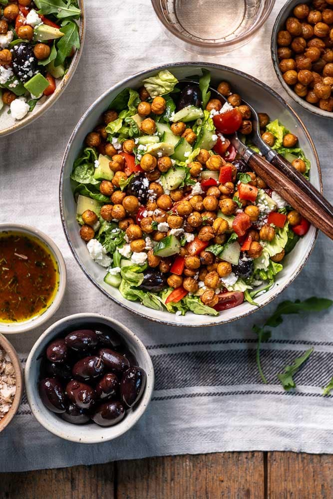 Kikkererwten salade met feta, geroosterde kikkererwten, rucola en balsamico dressing in een kom.