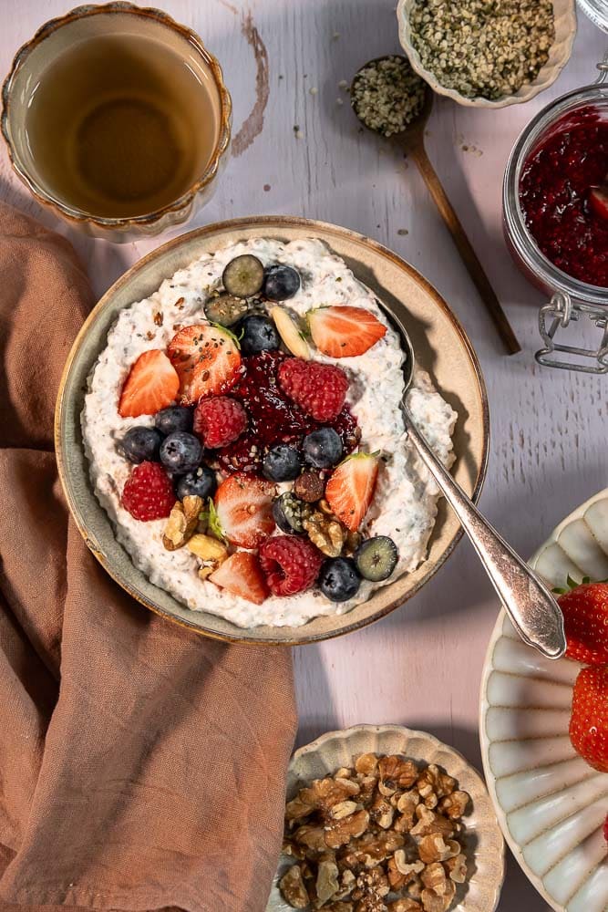 Gezonde overnight oats in een glas met zomerfruit en nootjes.