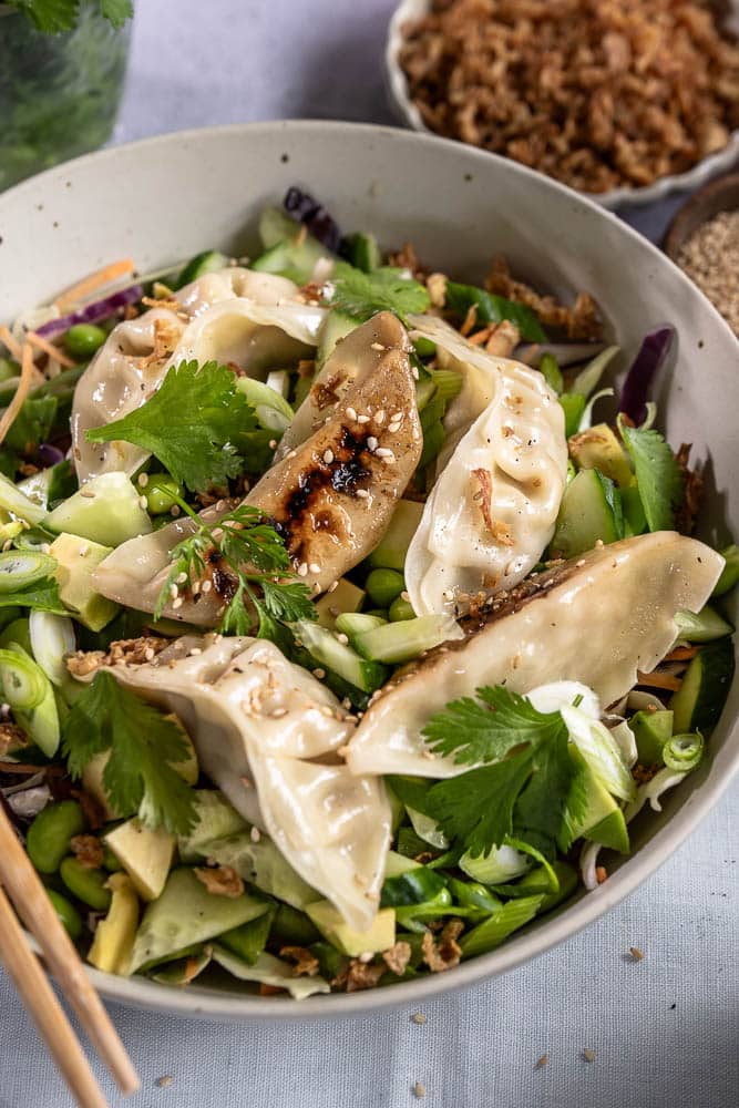 Frisse gyoza salade met kip gyoza, koolmix, edamame, avocado, komkommer, paprika en een Oosterse dressing. Makkelijke maaltijdsalade voor lunch of avondeten.