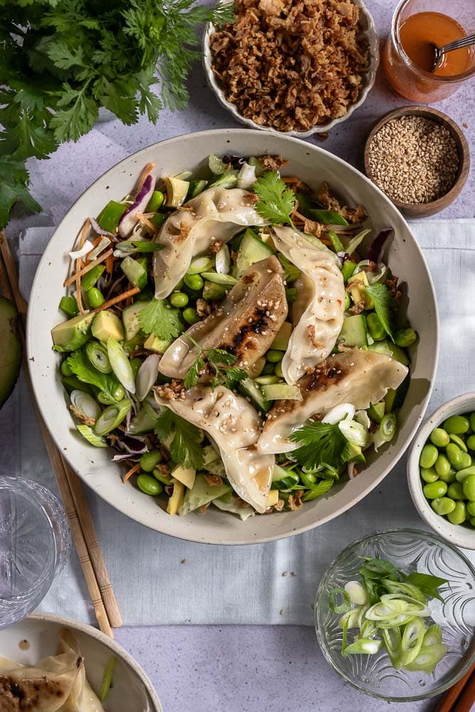 Frisse gyoza salade met kip gyoza, koolmix, edamame, avocado, komkommer, paprika en een Oosterse dressing. Makkelijke maaltijdsalade voor lunch of avondeten.