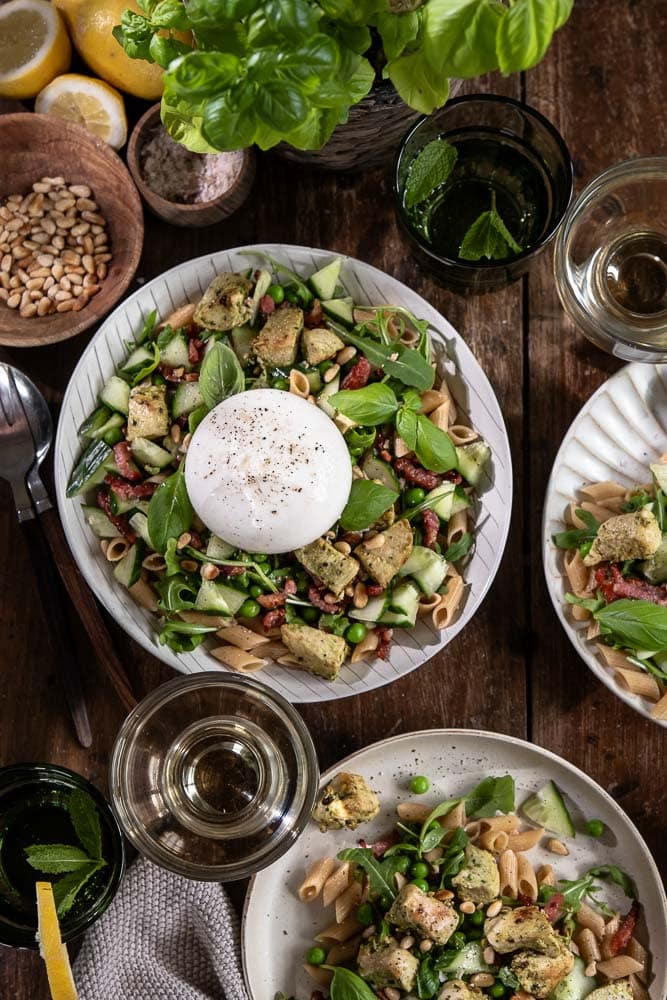Pastasalade met kip, volkoren pasta, burrata, pesto, spekjes, rucola en doperwten. Makkelijke Italiaanse maaltijdsalade voor lunch of avondeten.