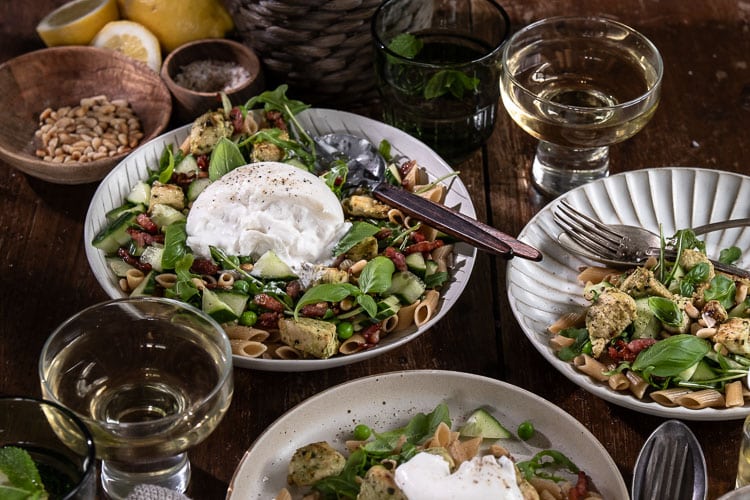 Pastasalade met kip, volkoren pasta, burrata, pesto, spekjes, rucola en doperwten. Makkelijke Italiaanse maaltijdsalade voor lunch of avondeten.
